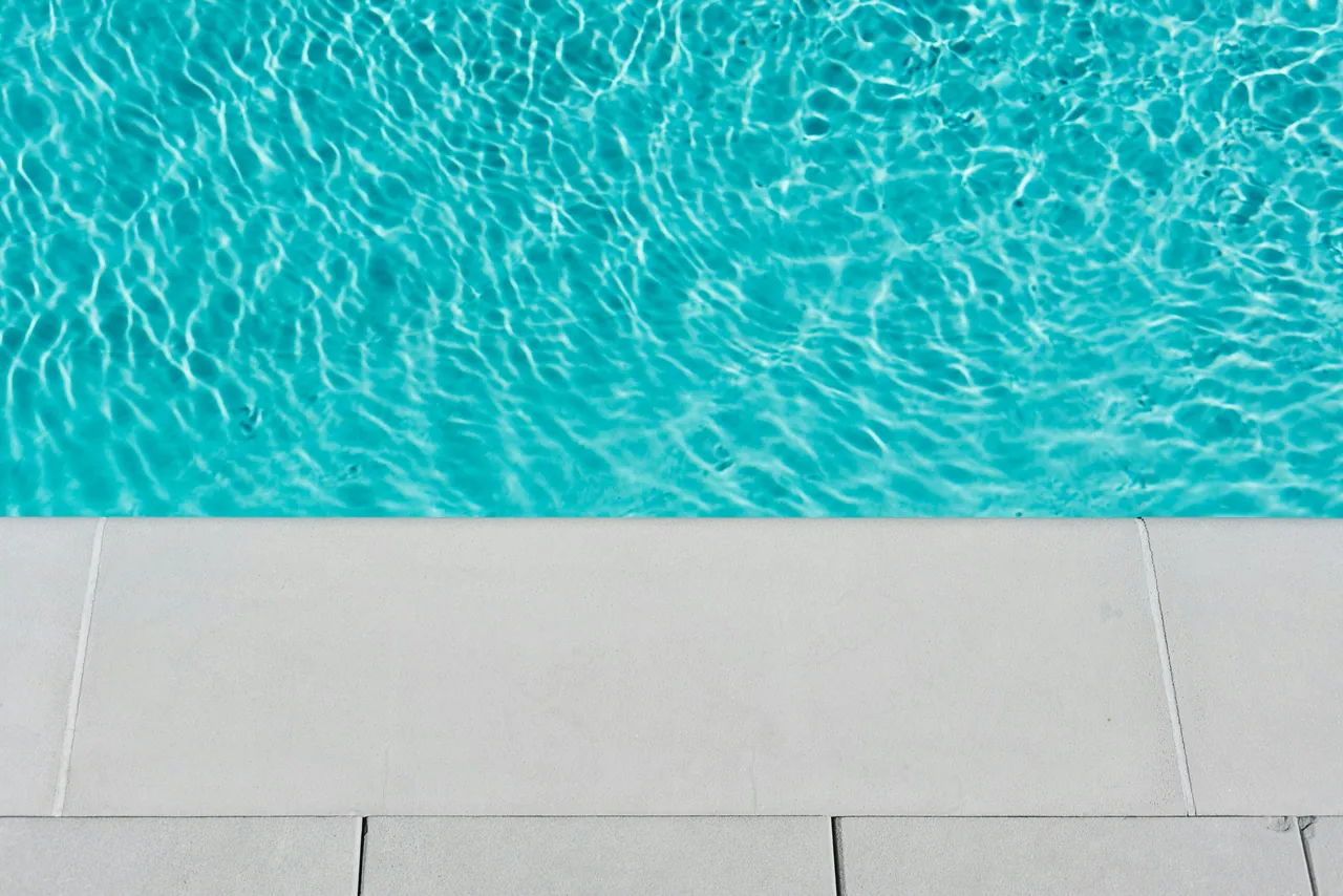 Clear pool water above a strip of pale stone coping.